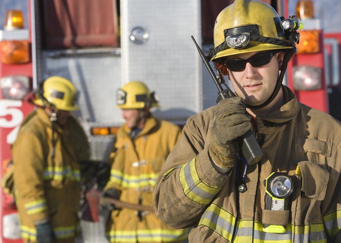 a photo of a group of firefighters with one on a walkie talkie.