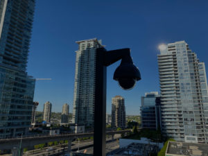 A photo of a cctv camera on a pole looking out over the city.