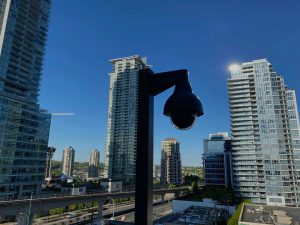 A photo of a cctv camera on a pole looking out over the city.